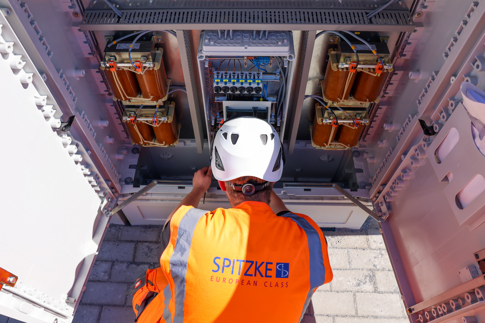 Ein Mitarbeiter in persönlicher Schutzausrichtung arbeitet an einem Stromkasten.