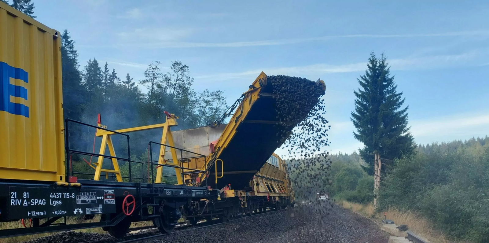 Ein MFS-Wagen verteilt Schotter im Gleisbett mit einem Förderband.